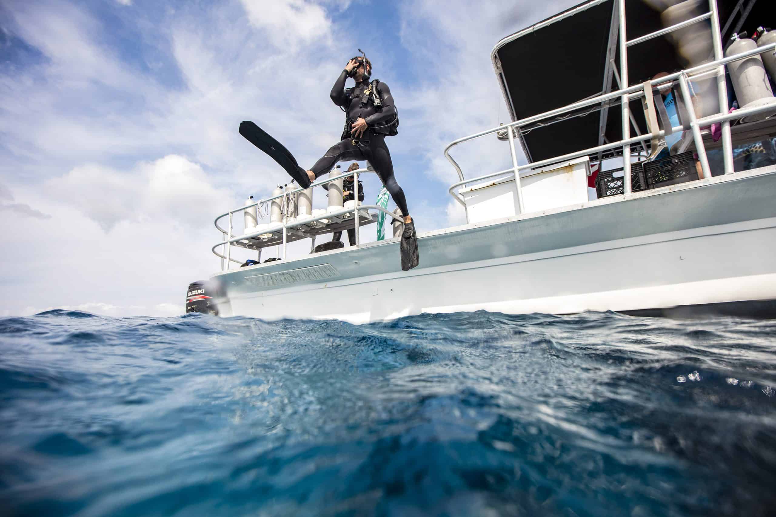 Local_PADI 6 A Diver performing a giant stride into the ocean off of a dive boat.